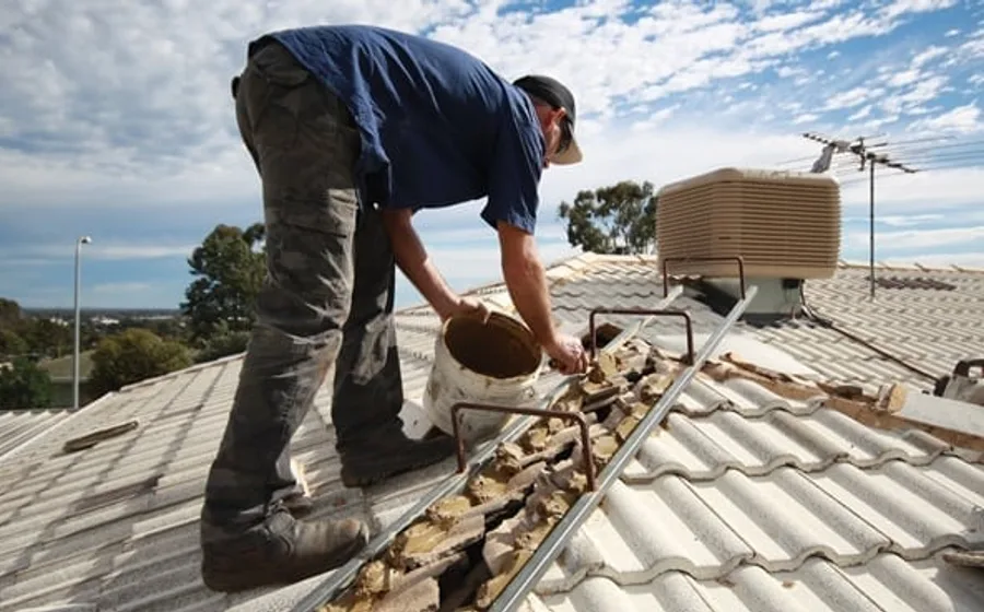 Ridge capping being re-bedded and repointed on a tiled roof